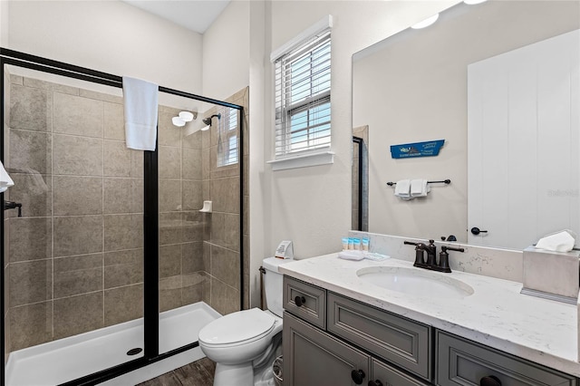 bathroom featuring wood-type flooring, an enclosed shower, vanity, and toilet