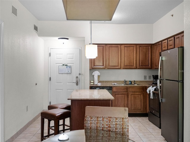 kitchen with light stone countertops, decorative light fixtures, a kitchen island, light tile floors, and appliances with stainless steel finishes