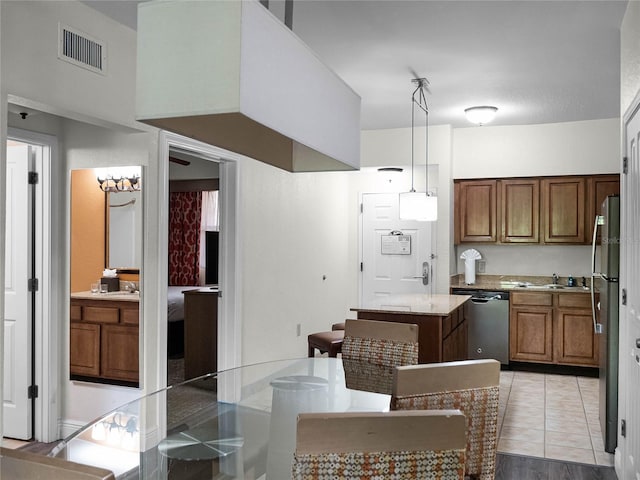 kitchen with stainless steel appliances, light tile flooring, pendant lighting, a center island, and sink