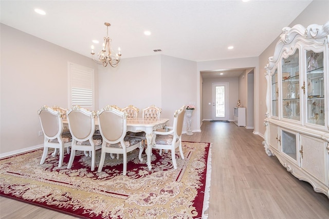 dining area featuring wood-type flooring and an inviting chandelier