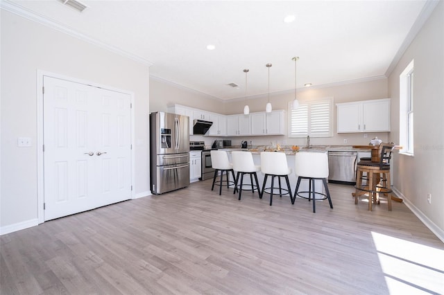 kitchen featuring light hardwood / wood-style floors, a kitchen island, hanging light fixtures, a kitchen bar, and appliances with stainless steel finishes