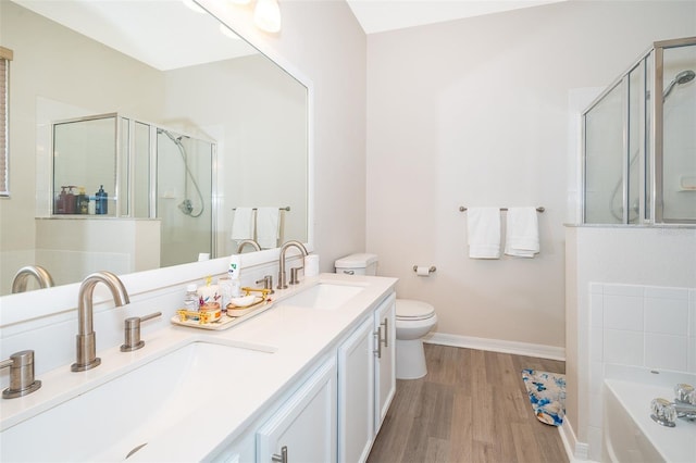 full bathroom with hardwood / wood-style floors, double sink vanity, toilet, and separate shower and tub