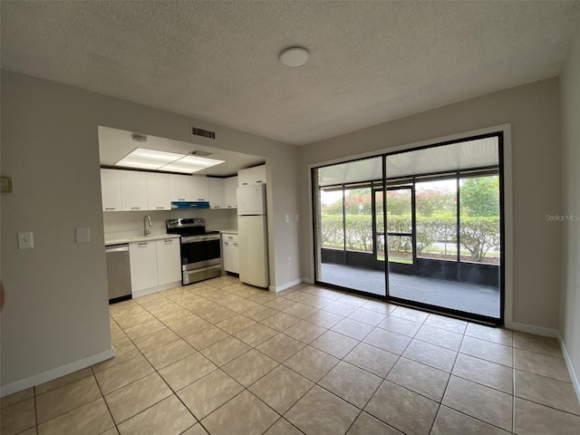 kitchen featuring appliances with stainless steel finishes, white cabinets, light tile patterned flooring, and sink