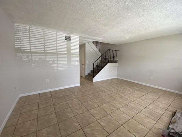 unfurnished room featuring a textured ceiling and light tile patterned flooring