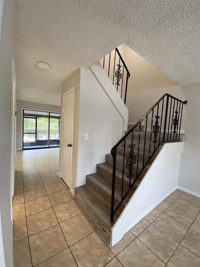 stairs with a textured ceiling and tile patterned flooring