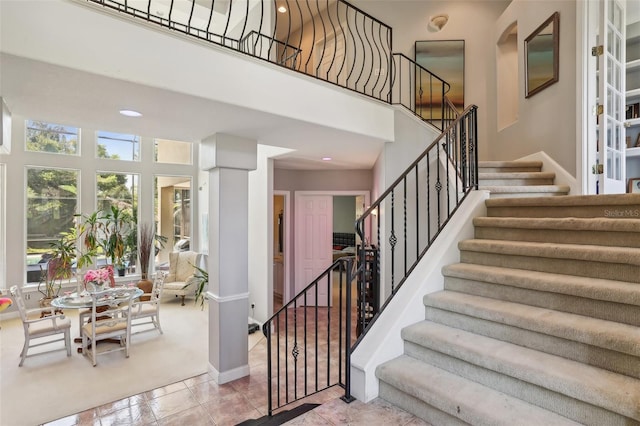 staircase with tile flooring and a high ceiling