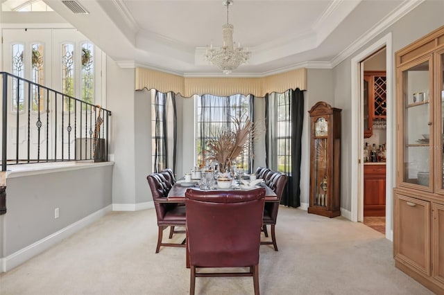 carpeted dining area with a wealth of natural light, an inviting chandelier, and a tray ceiling