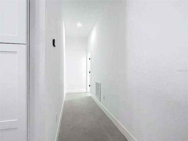 corridor featuring visible vents, concrete floors, and baseboards