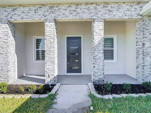 property entrance with a porch and stucco siding