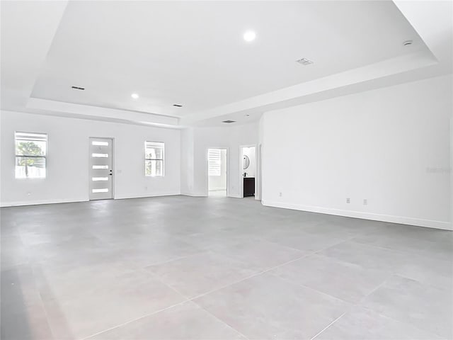 unfurnished living room with baseboards and a raised ceiling