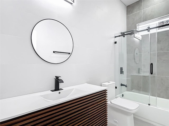 bathroom featuring vanity, toilet, tile walls, and shower / bath combination with glass door