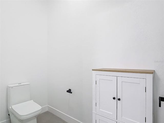 bathroom featuring baseboards and toilet