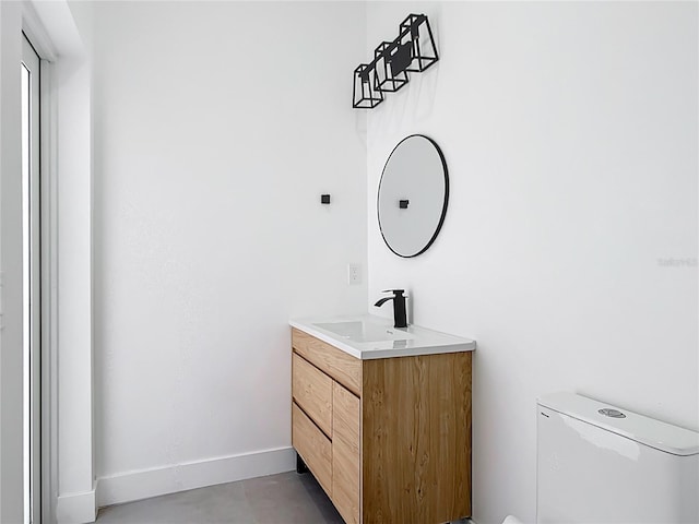 bathroom with toilet, vanity, and baseboards