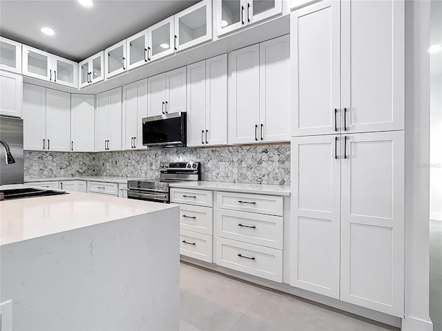 kitchen with decorative backsplash, appliances with stainless steel finishes, and white cabinetry