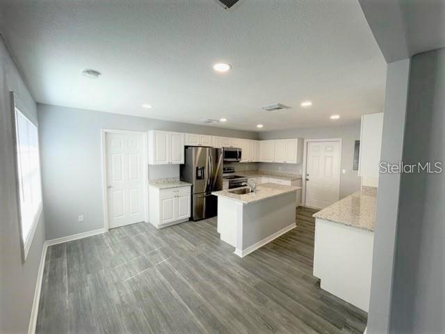 kitchen featuring a kitchen island, stainless steel appliances, hardwood / wood-style floors, and white cabinets