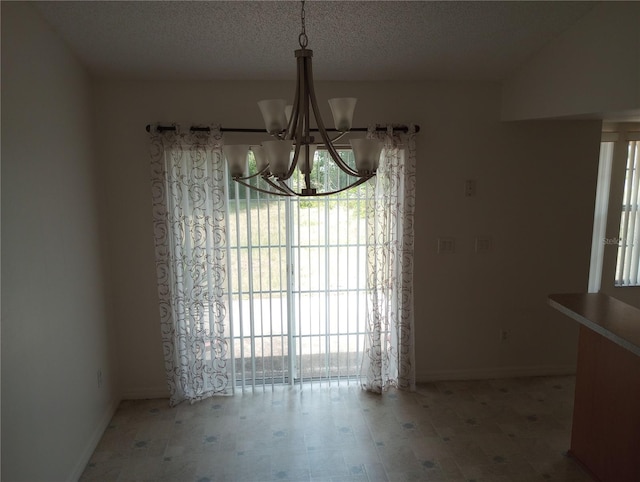 unfurnished dining area with a textured ceiling and a chandelier