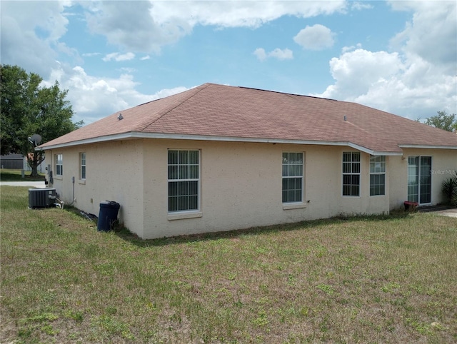 view of side of home with a lawn and cooling unit