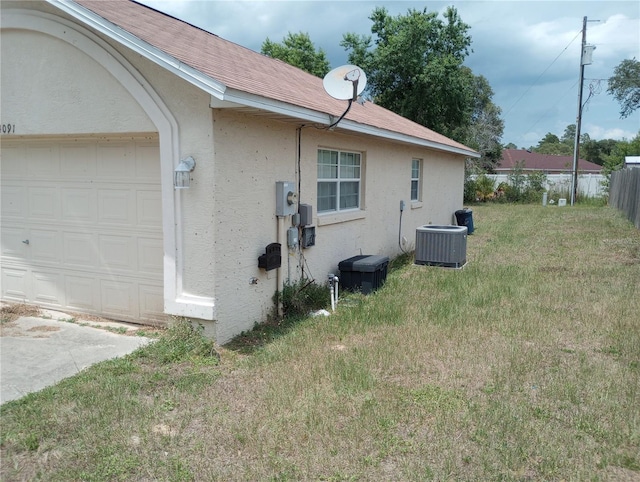 view of side of home featuring central air condition unit, a yard, and a garage