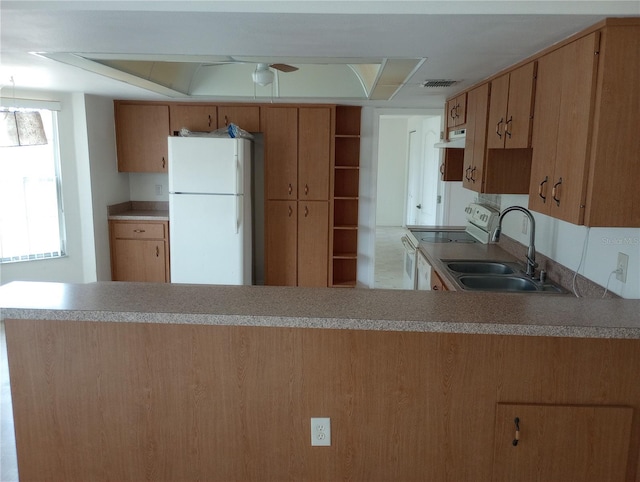 kitchen featuring kitchen peninsula, white appliances, and sink