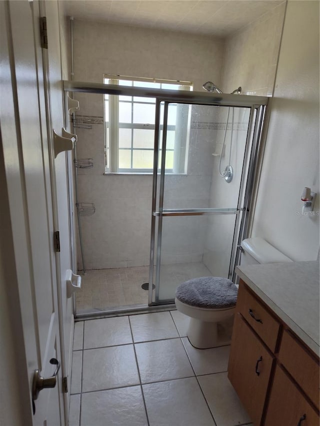 bathroom featuring tile patterned floors, vanity, toilet, and walk in shower