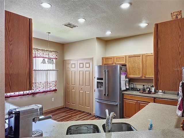 kitchen featuring stainless steel fridge with ice dispenser, dark wood-type flooring, a textured ceiling, and pendant lighting