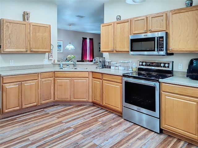 kitchen featuring decorative light fixtures, light wood-type flooring, light brown cabinetry, sink, and appliances with stainless steel finishes