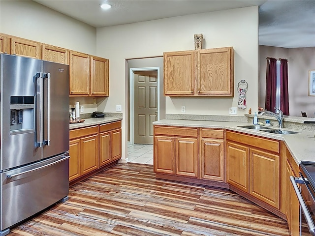 kitchen featuring high end refrigerator, sink, hardwood / wood-style flooring, and range