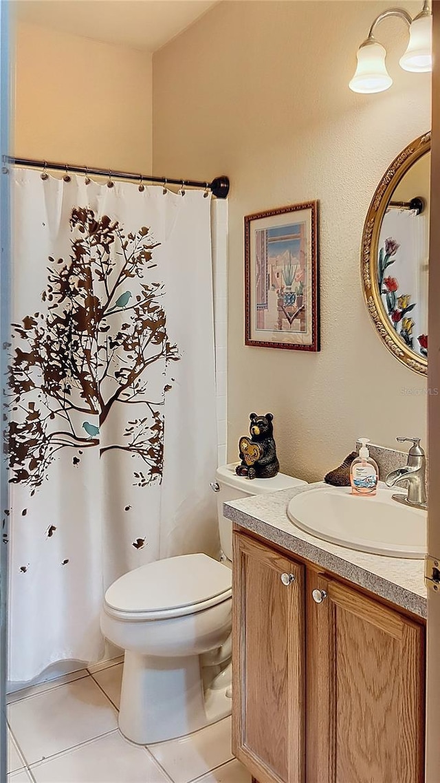 bathroom with tile flooring, toilet, and vanity