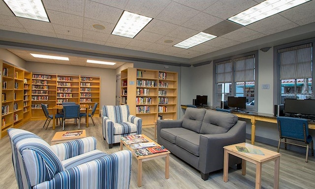 living room featuring wood-type flooring and a drop ceiling