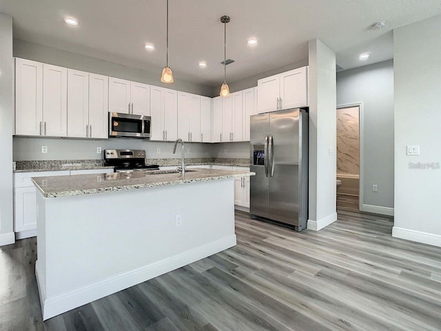 kitchen featuring stainless steel appliances, a kitchen island with sink, hardwood / wood-style flooring, and white cabinetry