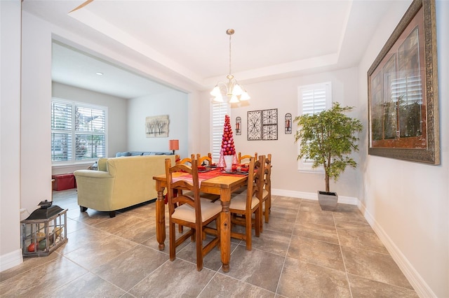 dining space featuring a raised ceiling and a notable chandelier