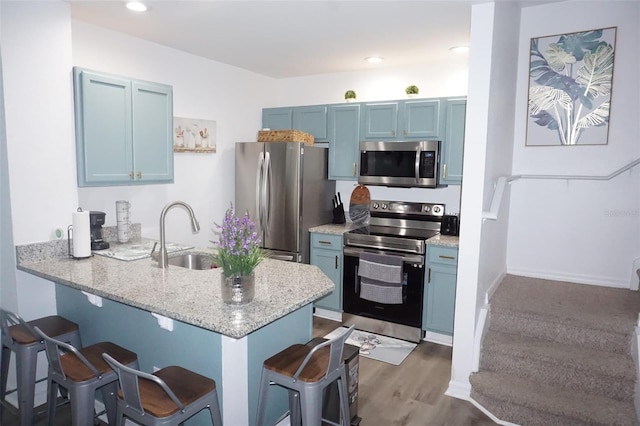 kitchen with kitchen peninsula, appliances with stainless steel finishes, a breakfast bar area, and sink