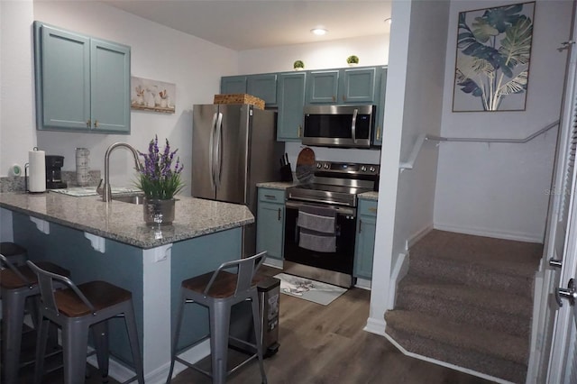 kitchen featuring light stone countertops, stainless steel appliances, dark hardwood / wood-style floors, kitchen peninsula, and a breakfast bar