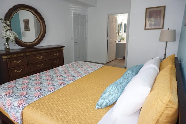 bedroom with hardwood / wood-style flooring and connected bathroom