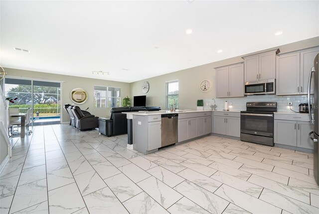 kitchen with kitchen peninsula, appliances with stainless steel finishes, tasteful backsplash, gray cabinetry, and sink