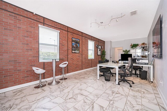 office space featuring plenty of natural light and brick wall