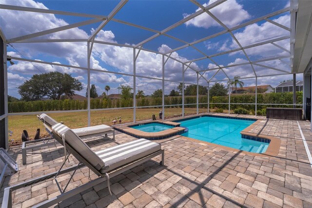 view of pool with an in ground hot tub, a patio, glass enclosure, and a lawn