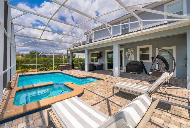 view of swimming pool featuring outdoor lounge area, glass enclosure, grilling area, an in ground hot tub, and a patio