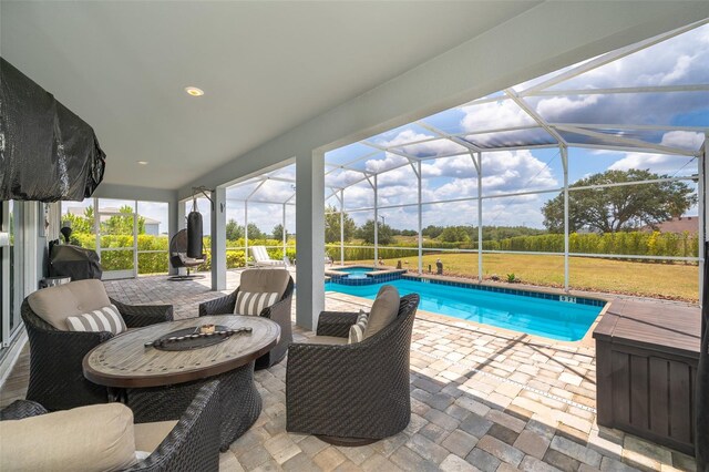 view of pool featuring glass enclosure, a patio area, an in ground hot tub, and an outdoor fire pit