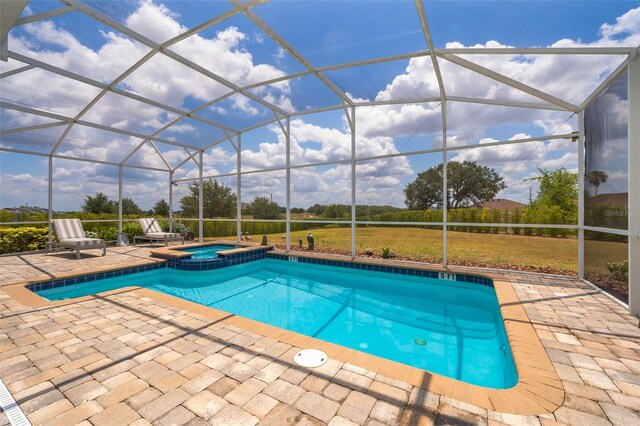 view of swimming pool with glass enclosure, an in ground hot tub, and a patio area