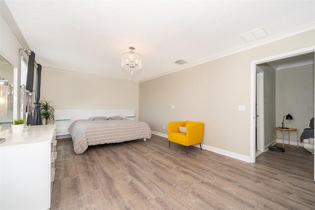 bedroom featuring an inviting chandelier, ornamental molding, and hardwood / wood-style flooring