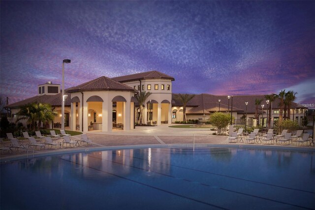 pool at dusk featuring a patio