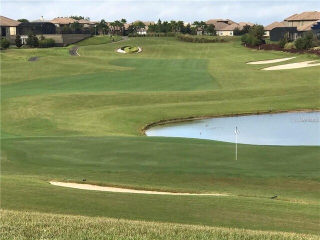 surrounding community with a water view and a lawn