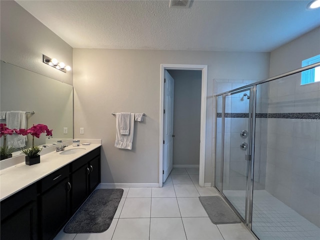 bathroom featuring tile patterned flooring, vanity, an enclosed shower, and a textured ceiling