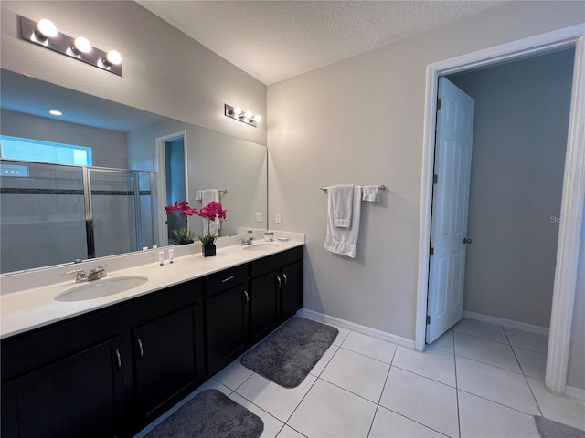 bathroom with tile patterned flooring, vanity, a shower with door, and a textured ceiling