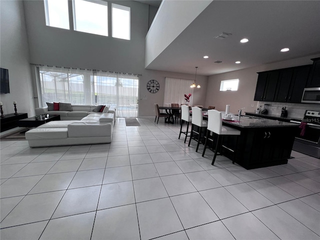 living room featuring a wealth of natural light, sink, light tile patterned flooring, and a notable chandelier