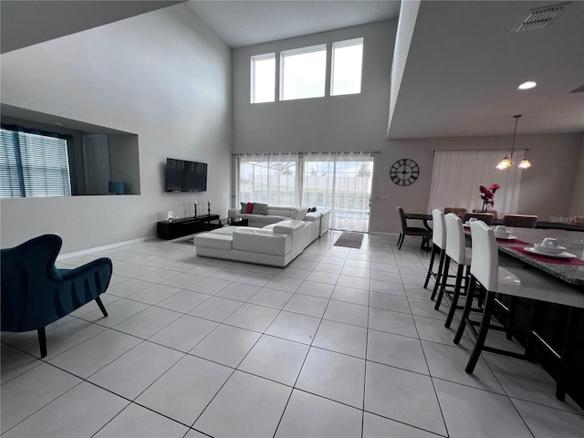 tiled living room featuring a high ceiling and a notable chandelier