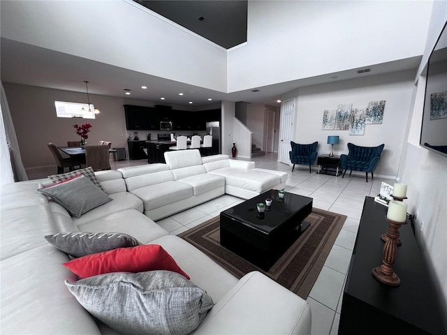 living room with a notable chandelier, light tile patterned floors, and a towering ceiling