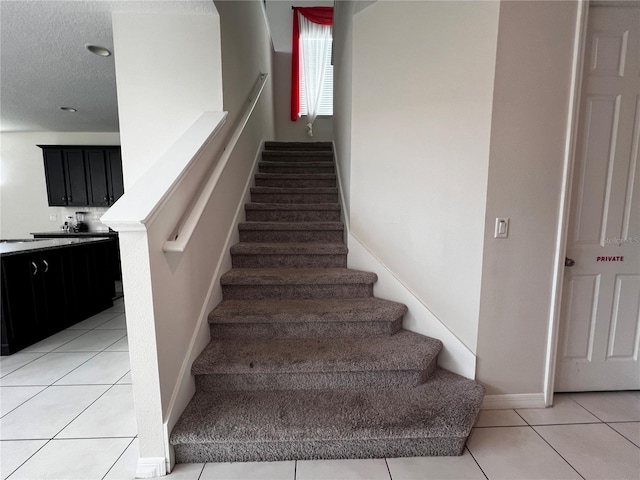 stairs with a textured ceiling and tile patterned floors