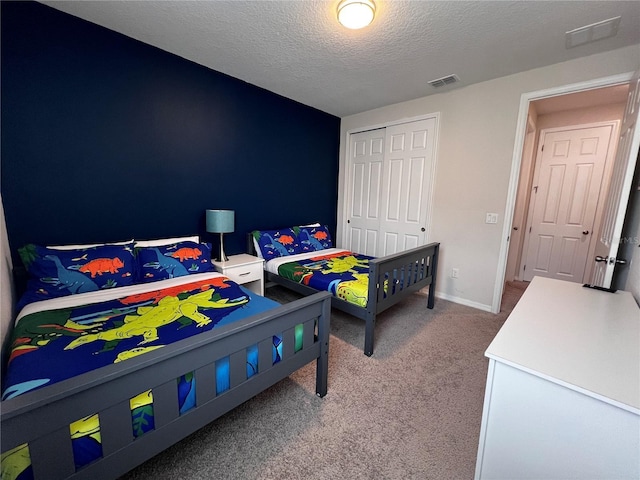 carpeted bedroom featuring a textured ceiling and a closet